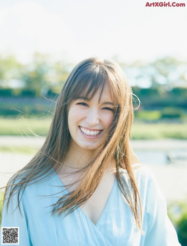 A woman in a blue dress smiles at the camera.