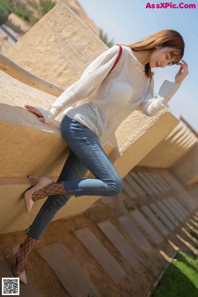 A woman leaning against a wall with her hand on her head.