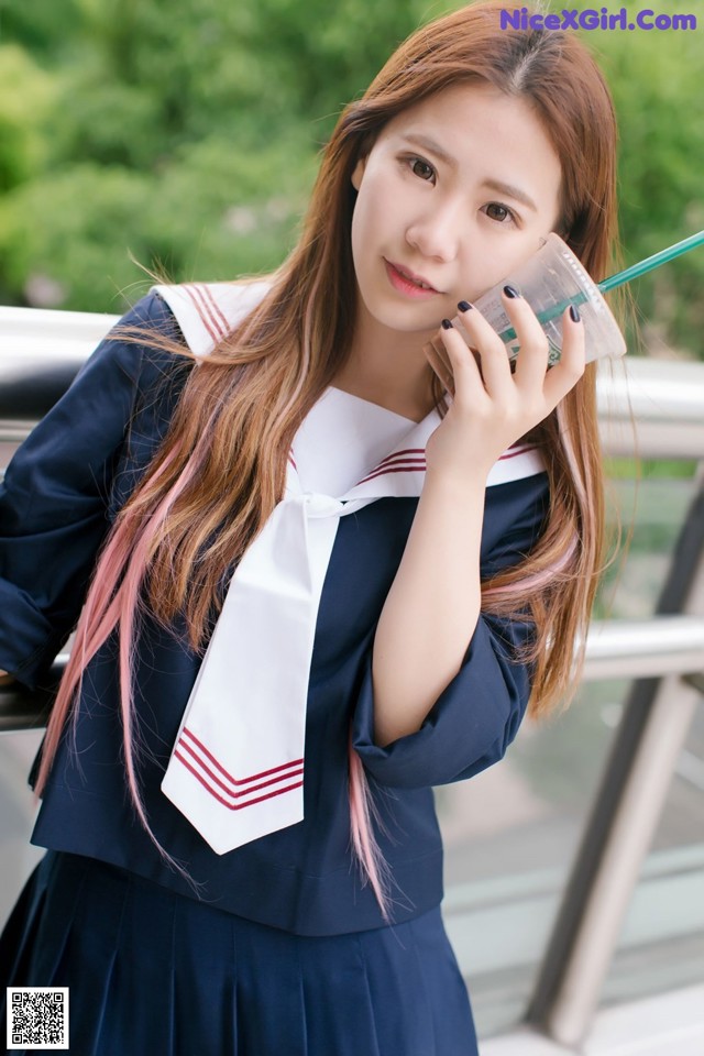 A woman in a school uniform talking on a cell phone.