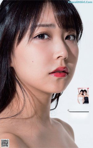 A woman laying on top of a bed next to a magazine.