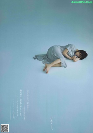 A woman laying on top of a bed next to a book.