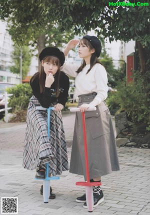 Two young women standing next to each other on a sidewalk.