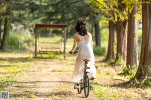 A woman in a white dress walking down a dirt road.