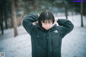 A woman in a bikini sitting in the snow.