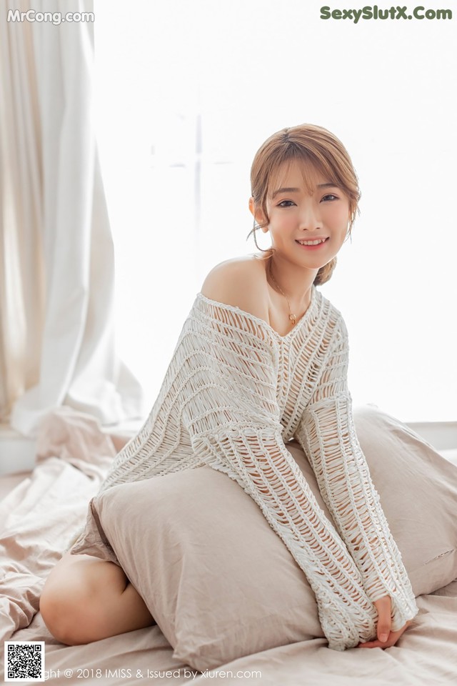 a woman sitting on top of a bed next to a window