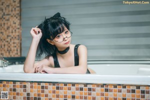 A woman in a black bathing suit sitting in a bathtub.