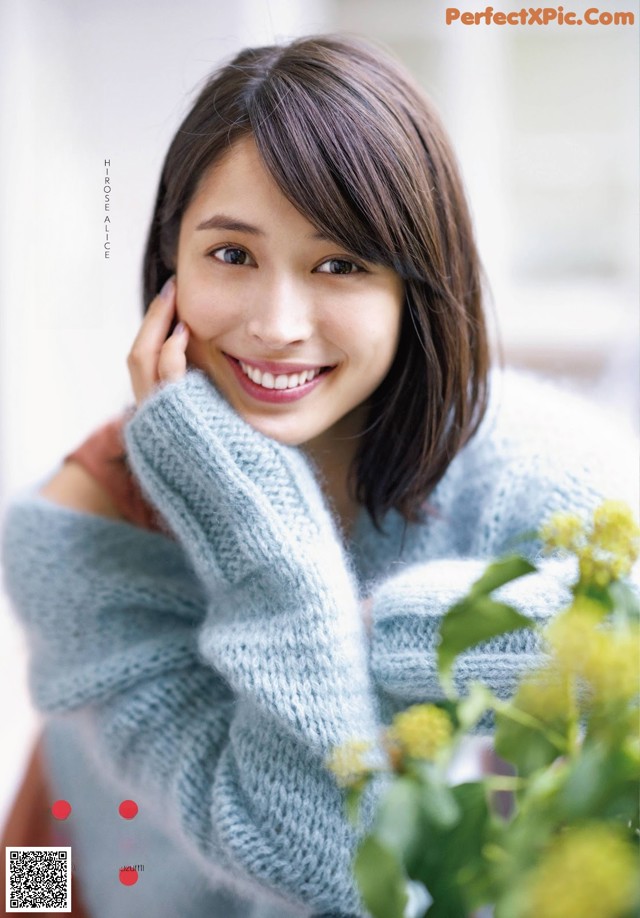 A woman in a blue sweater smiles at the camera.