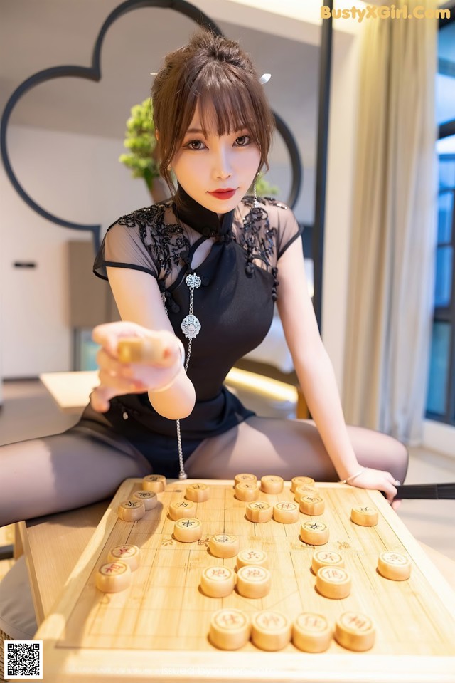 A woman sitting on top of a wooden table playing a game of chinese checkers.