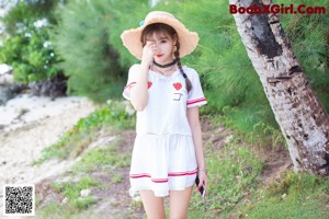 A woman in a white bikini and a straw hat on the beach.