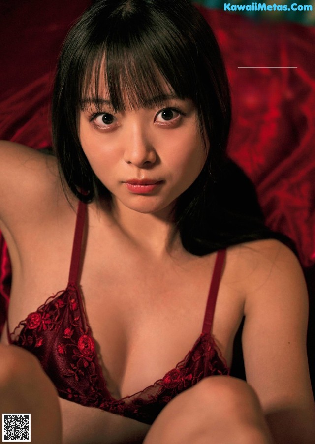 A woman in a red lingerie sitting on a bed.