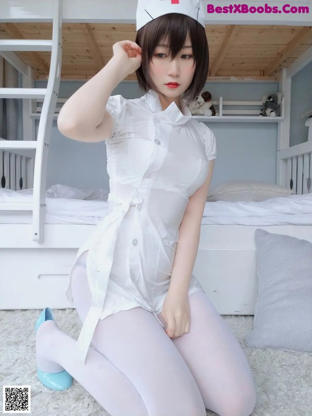 A woman in a white nurse outfit sitting on a bed.