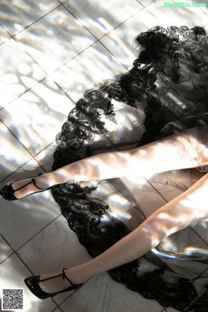 A woman in a black dress and high heels laying on the floor.