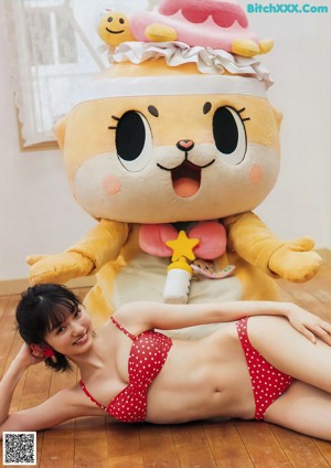 A woman in a red and white polka dot bikini sitting on a bed.