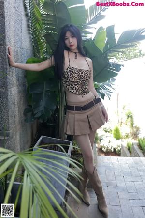 A woman in a leopard print top and skirt sitting on a couch.