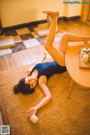 A woman sitting on a bed wearing a purple and white robe.