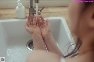 A woman in a white lingerie standing in a kitchen.