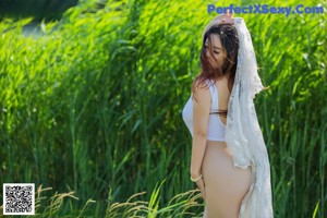 A woman in a white dress standing in tall grass.