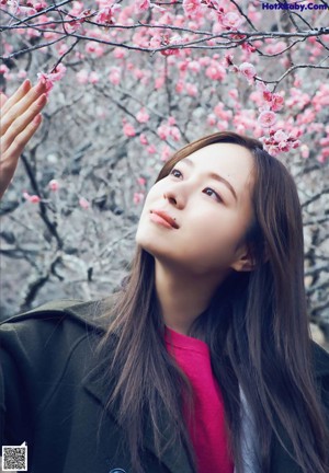 A woman standing in front of a flowering tree.