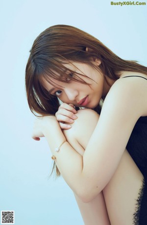 A woman in a white shirt and blue pleated skirt posing for a picture.