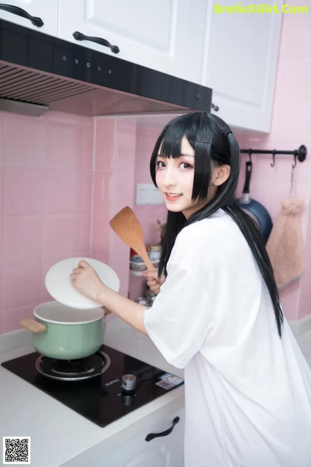 A woman in a white shirt is preparing food in a kitchen.