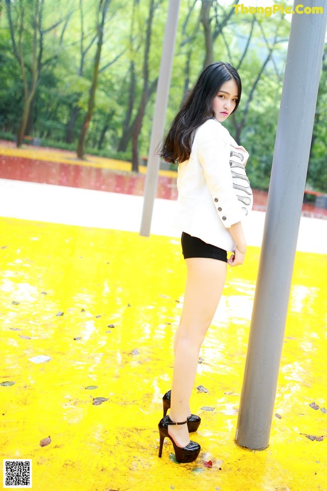 A woman in a white jacket and black shorts posing for a picture.