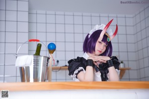 A woman dressed as a maid holding a metal bucket.