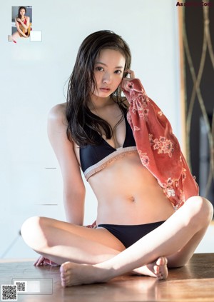 A woman in a black bathing suit leaning against a wall.