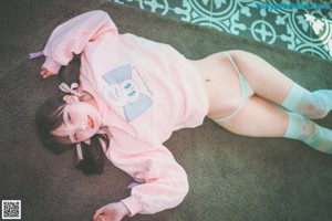 A woman in a pink sweatshirt and blue panties sitting on a swing.