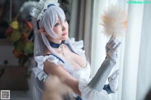 A woman in a maid outfit sitting on a window sill.