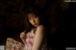 A woman in a floral dress standing in a cave.