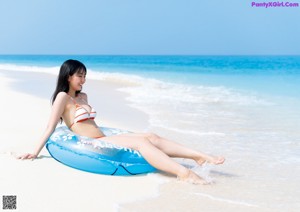A woman in a white bikini sitting on the floor.