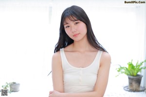 A woman in a white tank top posing for a picture.