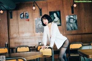A woman sitting at a bar with her finger on her lips.