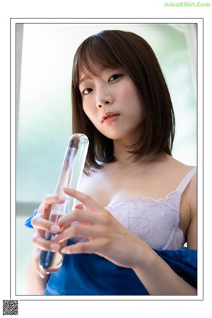 A woman in a blue top and white skirt sitting on the ground.